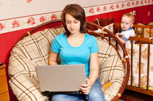 Молодая мама сидит за ноутбуком и ищет способы как заработать