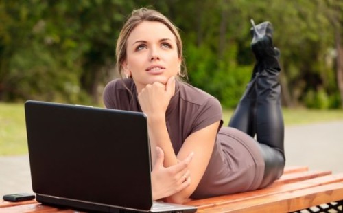 Красивая девушка мечтает за ноутбуком