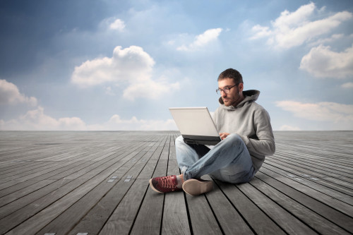 Парень сидит на крыше с ноутбуком в руках