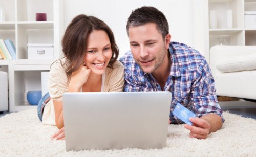 Муж и жена лежат на диване за ноутбуком